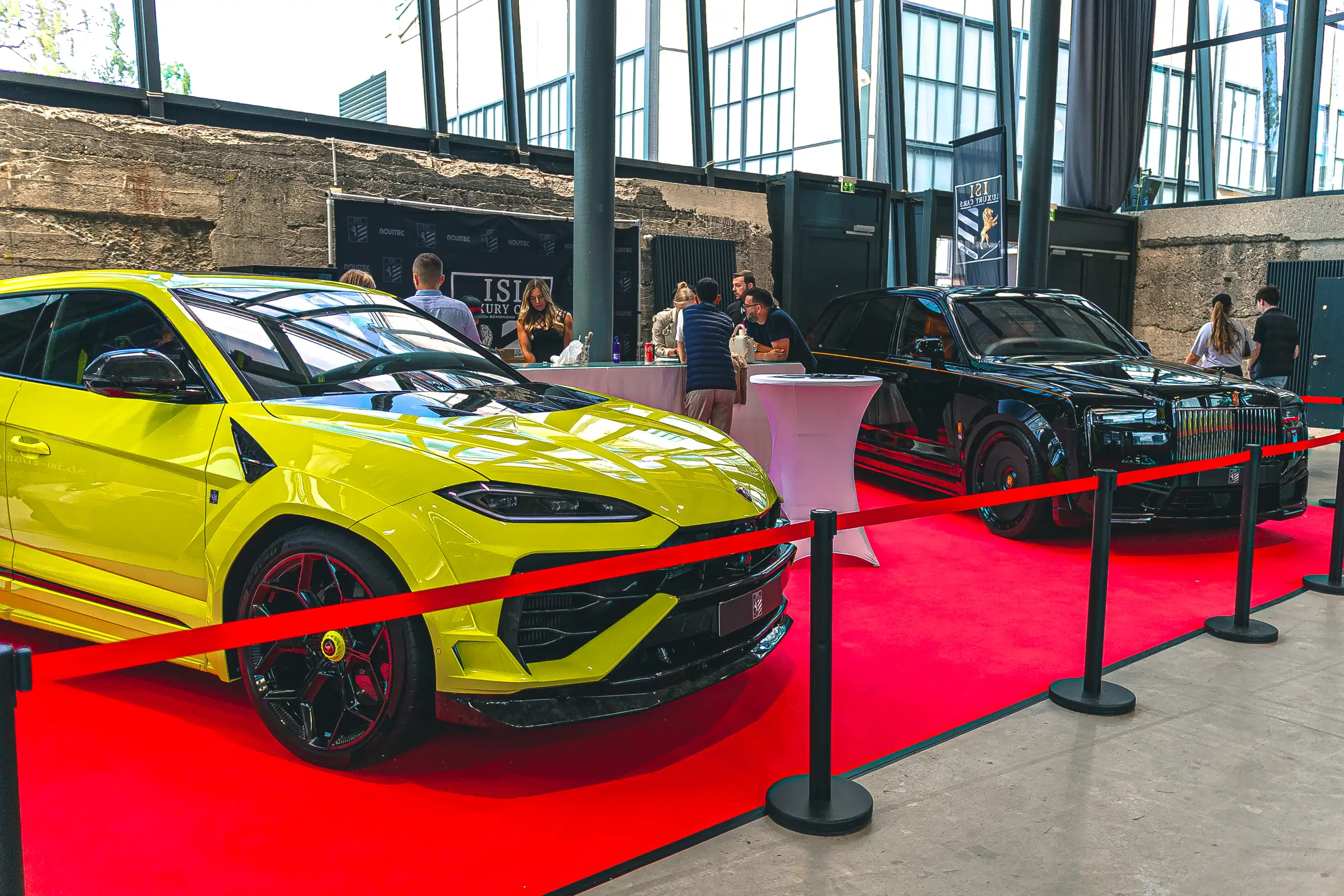 Gelber Lamborghini Urus und schwarzer Rolls-Royce auf dem roten Teppich