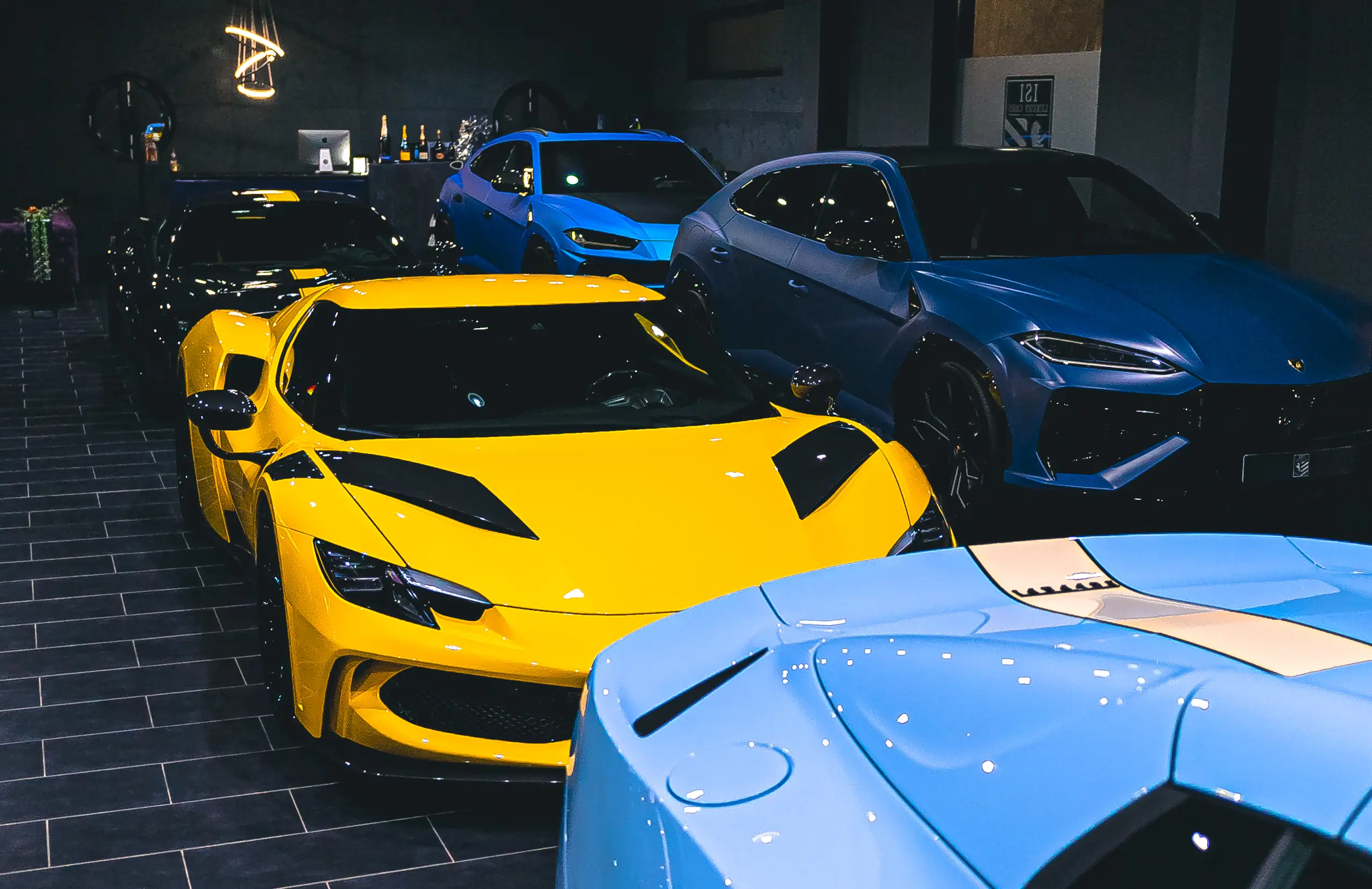 Gelber Ferrari neben einem hellblauen Ferrari und einem blauen Lamborghini Urus