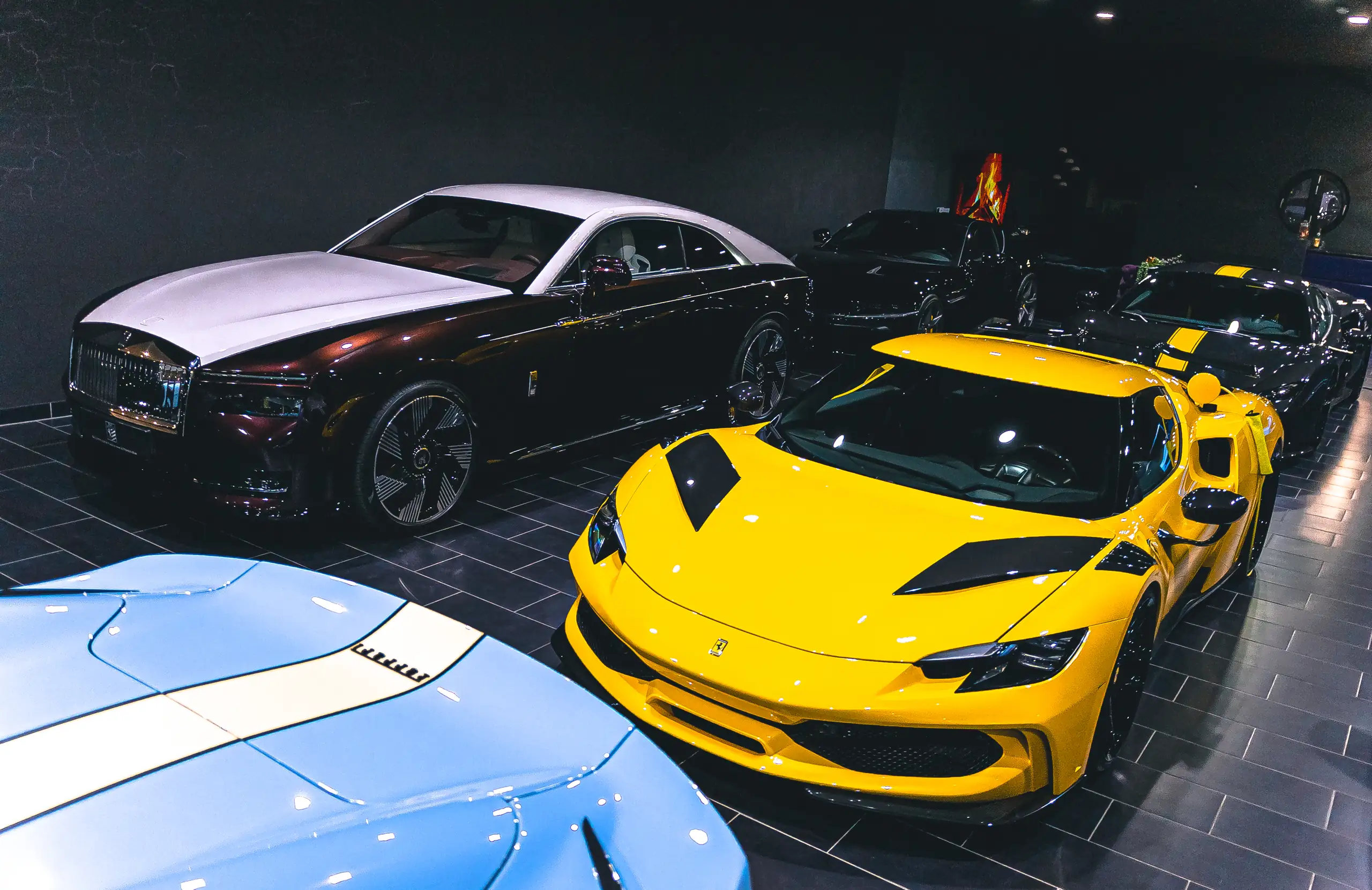 Gelber Ferrari von vorne, im Hintergrund ein Rolls-Royce Spectre