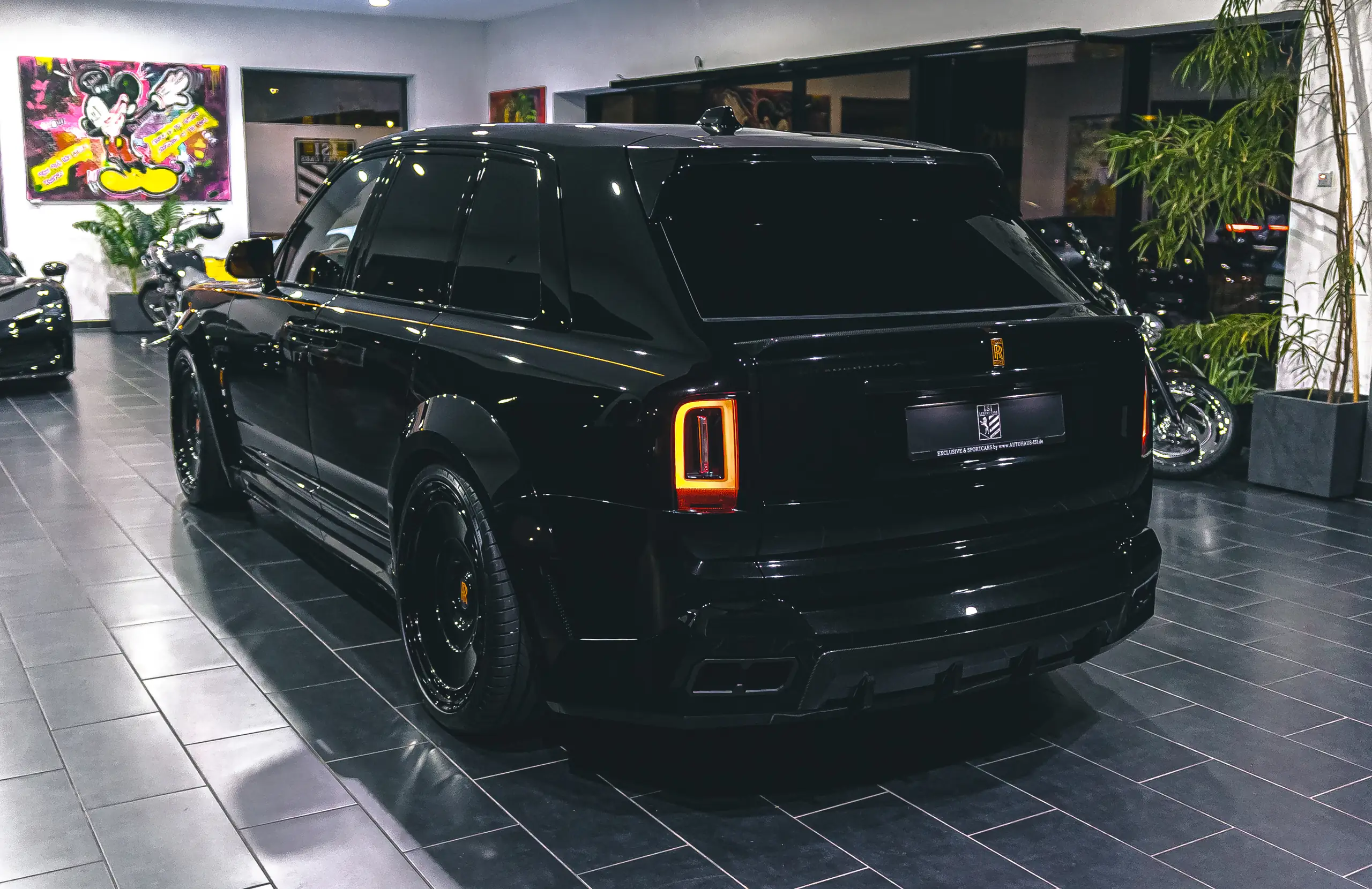 Schwarzer Rolls-Royce Cullinan von hinten, dahinter die Pop-Art-Wand