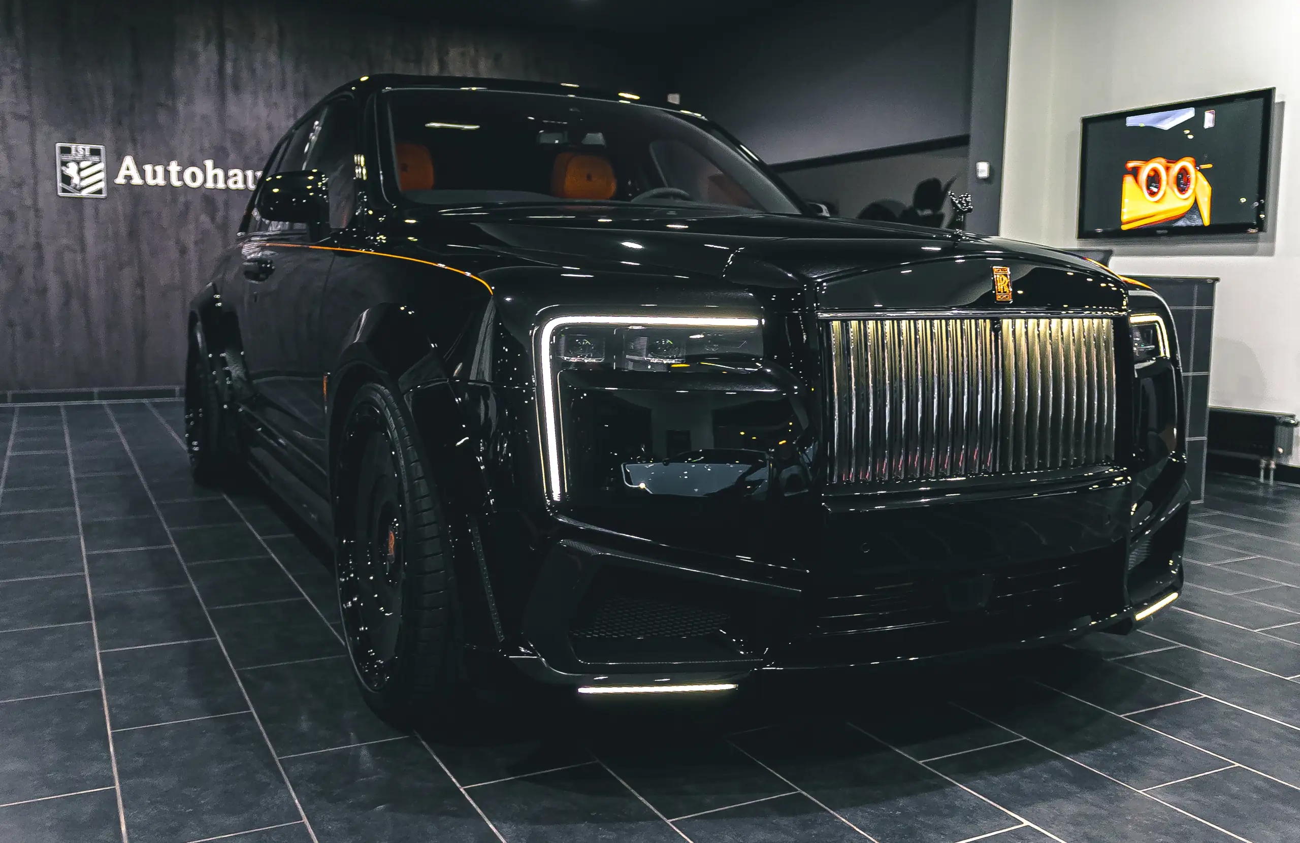 Schwarzer Rolls-Royce Cullinan vor der Wandbeschriftung Autohaus ISI