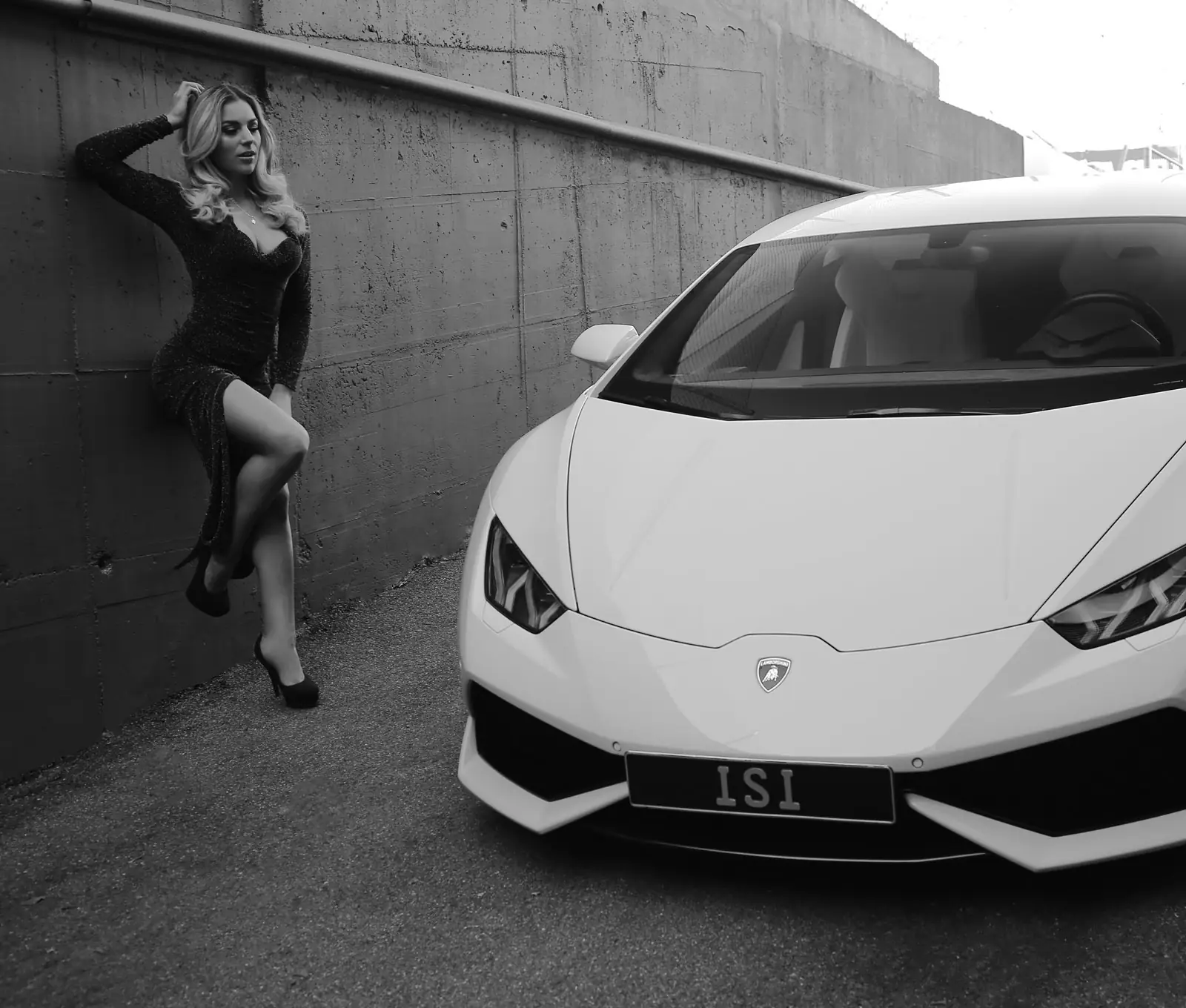 Modelshooting mit einem weißen Lamborghini Huracán vor einer Betonwand, Schwarz-Weiß-Aufnahme