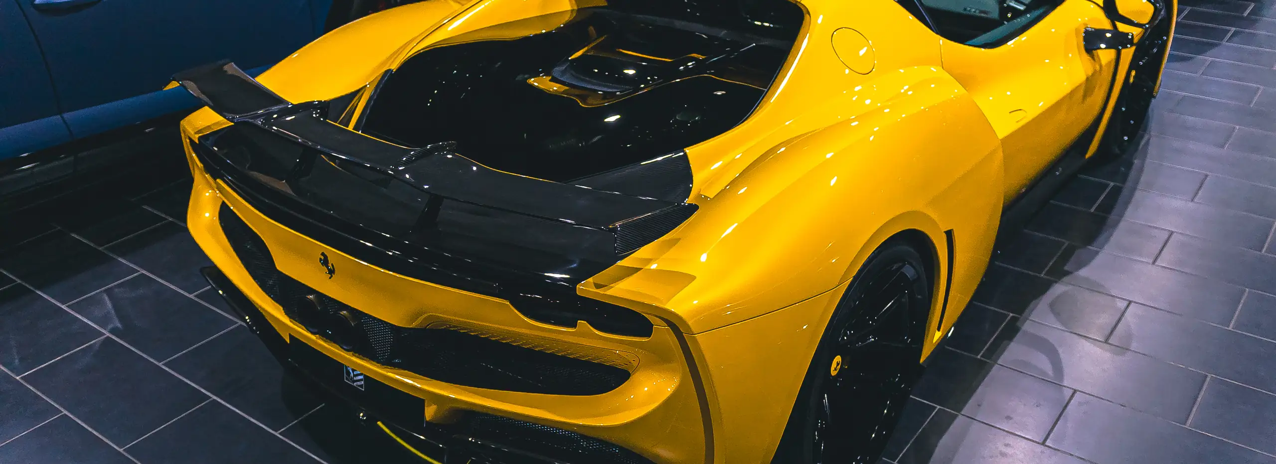 Gelber Ferrari mit Carbon-Heckflügel im Showroom von Autohaus ISI